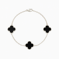 Silver bracelet with black clover-shaped charms on a white background