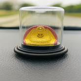 Yellow and red object in a glass dome on a black surface with blurred green background
