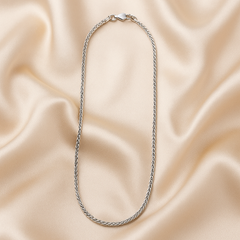 Silver chain necklace on a beige satin background