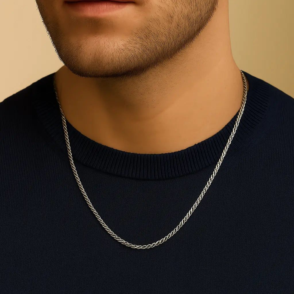 Silver chain necklace worn by a person on a beige background