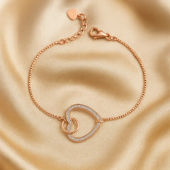 Rose gold bracelet with heart design on a beige fabric background