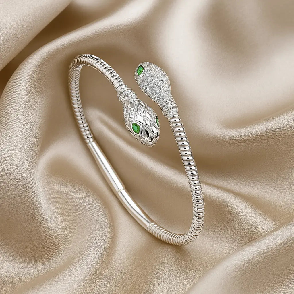 Silver snake-shaped bracelet with green eyes on a beige fabric background