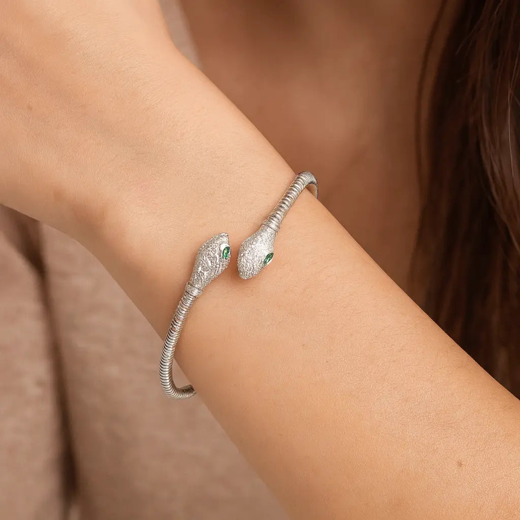 Silver snake bracelet on a wrist with a neutral background