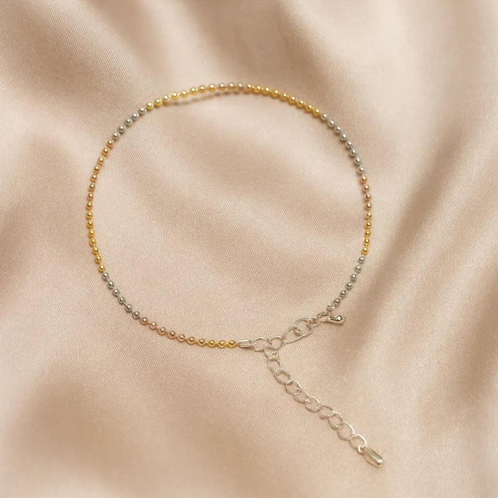 Anklet with multicolored beads on a beige fabric background