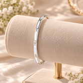 A slim silver bangle bracelet with three inlaid white mother-of-pearl segments and small clear stones
