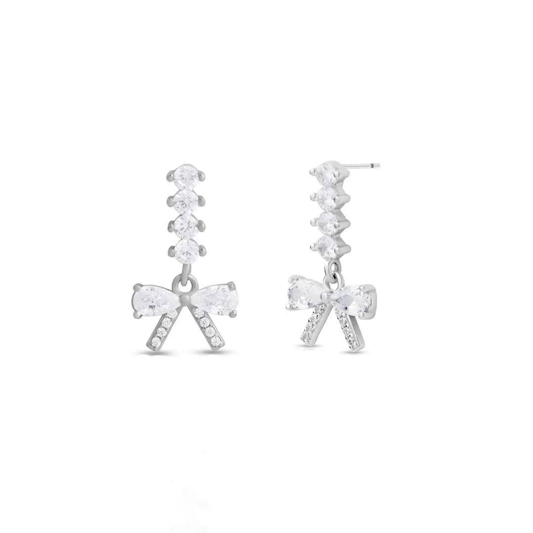 Silver bow-shaped earrings with clear gemstones on a white background