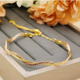 Gold bracelet on a gray jewelry box with flowers in the background