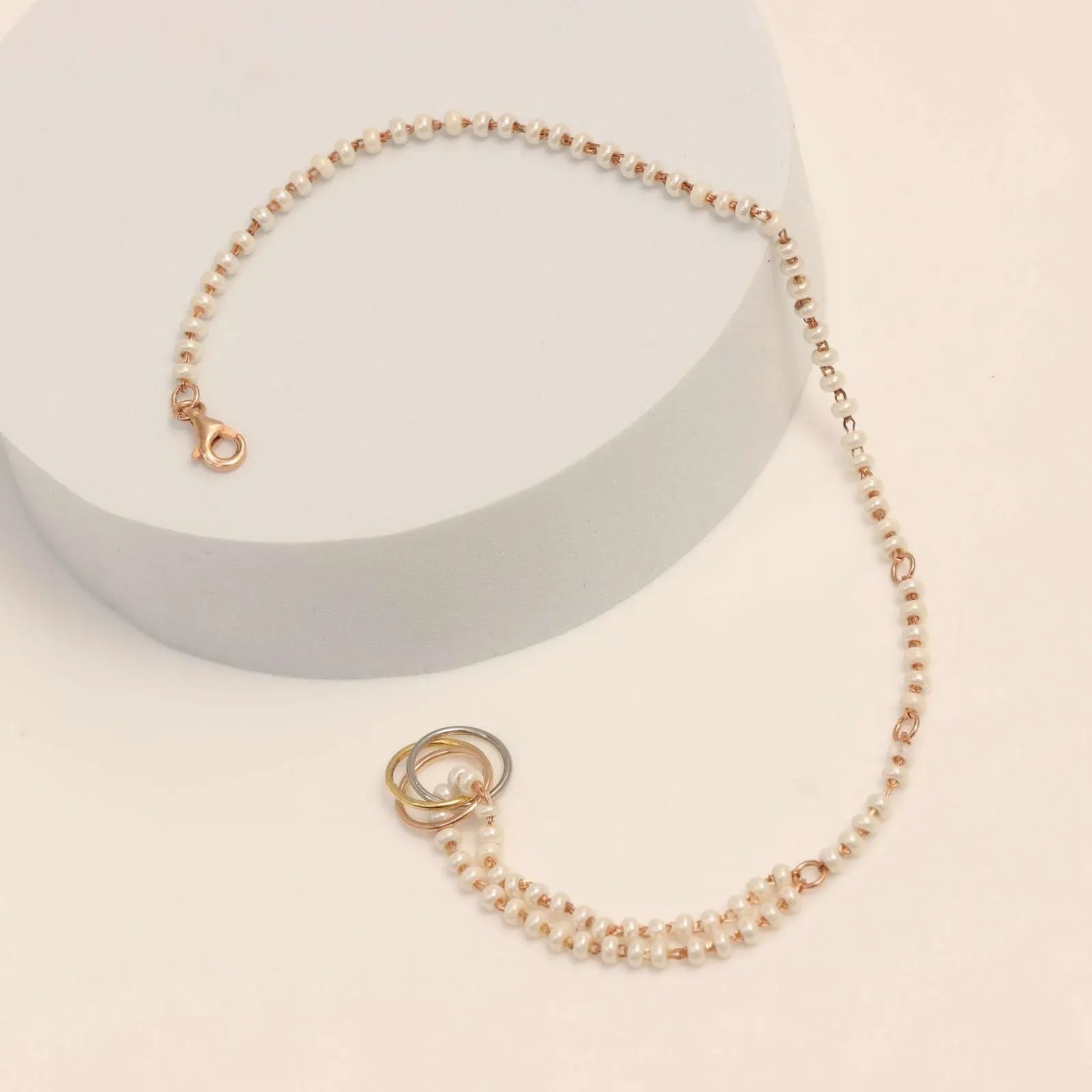 Pearl bracelet with gold clasp on a light beige background