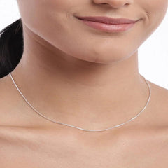 Silver necklace on a person with a neutral background