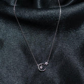 Silver necklace with a moon and star pendant on a dark fabric background
