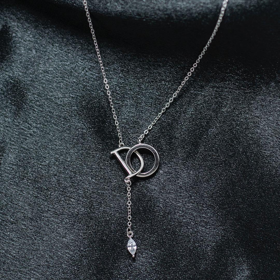 Silver necklace with a pendant on a dark fabric background