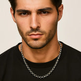 Man wearing a silver chain necklace against a neutral background