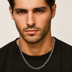 Man wearing a silver chain necklace against a neutral background