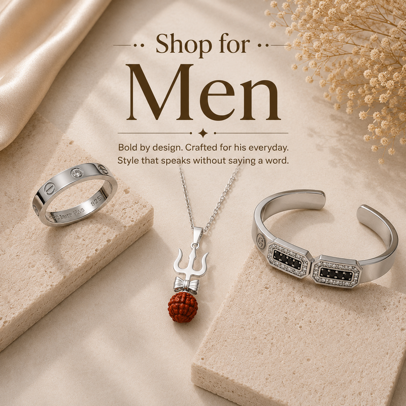 A styled jewelry set for men displayed on beige stone blocks with decorative fabric and dried flowers. 