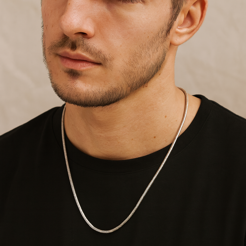 Man wearing a silver chain necklace against a neutral background
