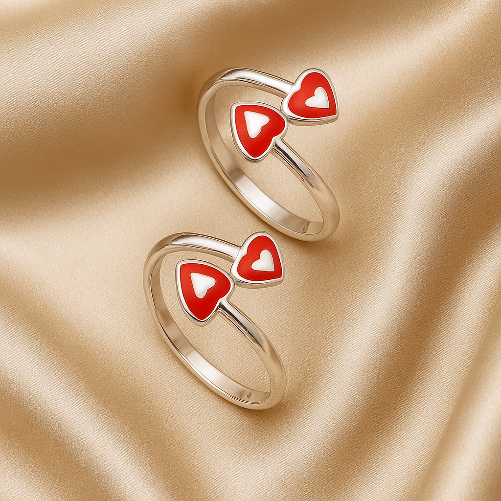 Two gold rings with red heart-shaped designs on a beige fabric background