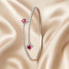 Silver bracelet with red gemstones on a beige satin background