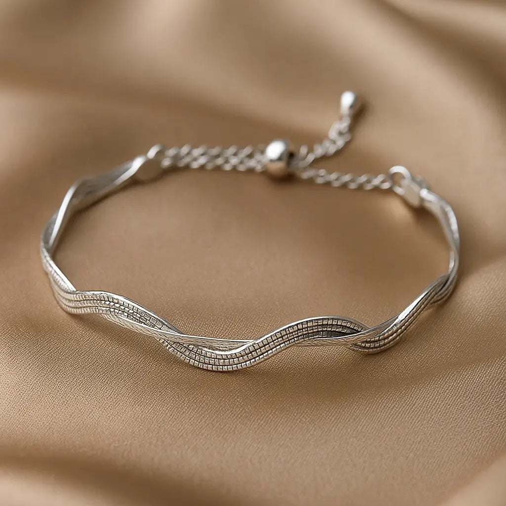 Silver bracelet with wavy design on a beige fabric background
