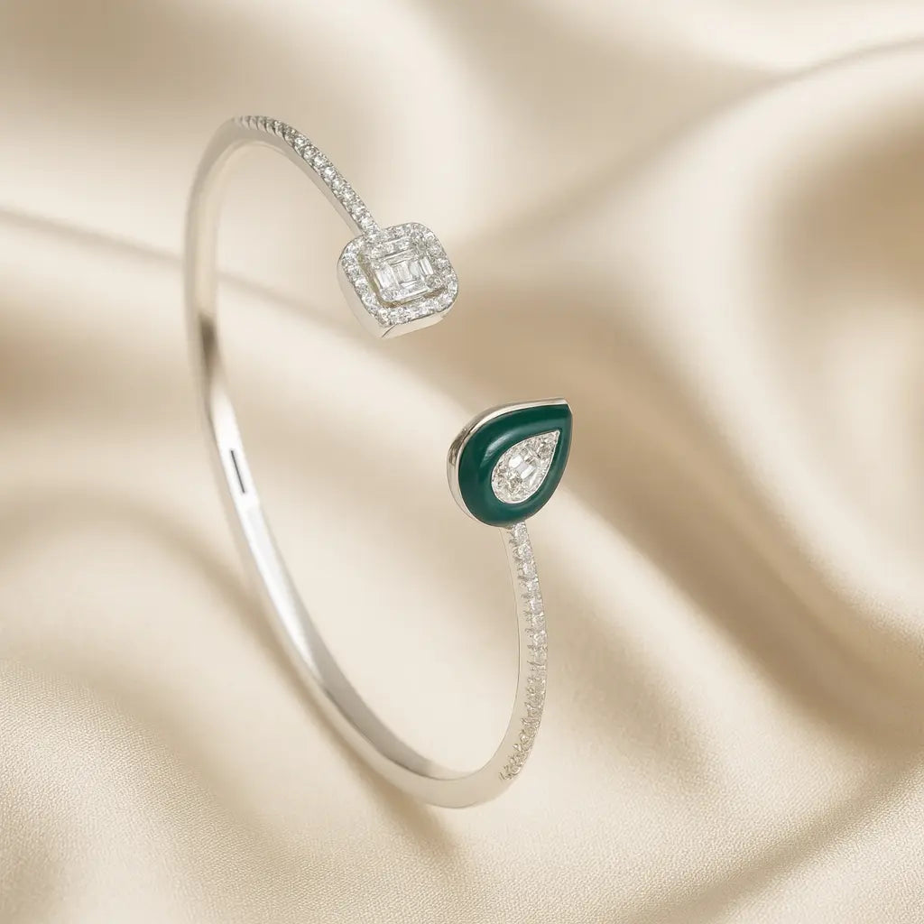 Silver bracelet with green teardrop charm on a beige satin background