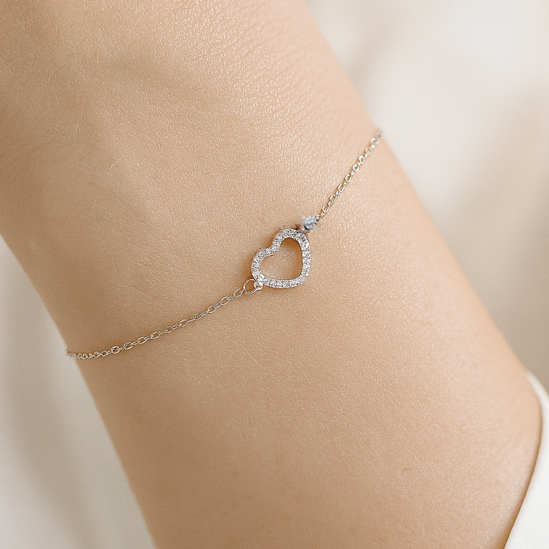 Silver anklet with a heart-shaped clasp on a person's ankle against a neutral background