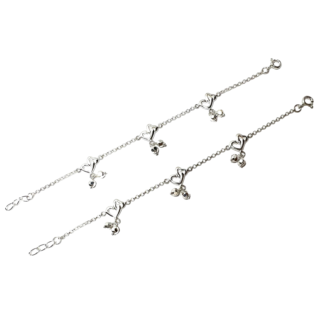 Silver bracelet with heart and bow charms on a white background